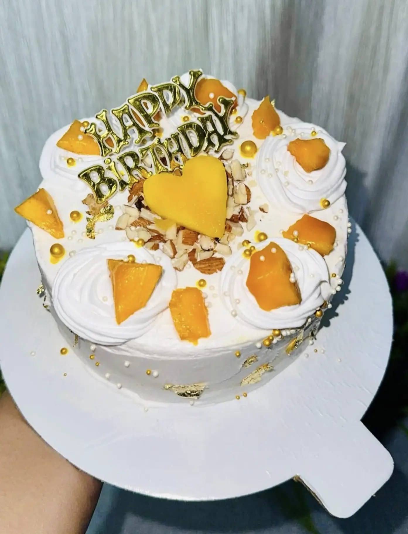 Mango cream cake finished with gold pearls